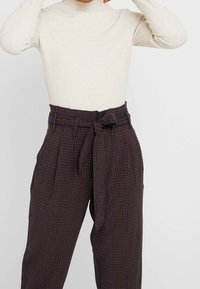 Hoch taillierte, karierte Hose in dunklen Tönen mit einem Selbstbindegürtel. Aus leichtem Stoff gefertigt, mit weitem Schnitt und Falten-Details.