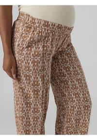 Brązowe spodnie w wzory z białym abstrakcyjnym wzorem, wykonane z lekkiego materiału, z elastycznym pasem dla większego komfortu.