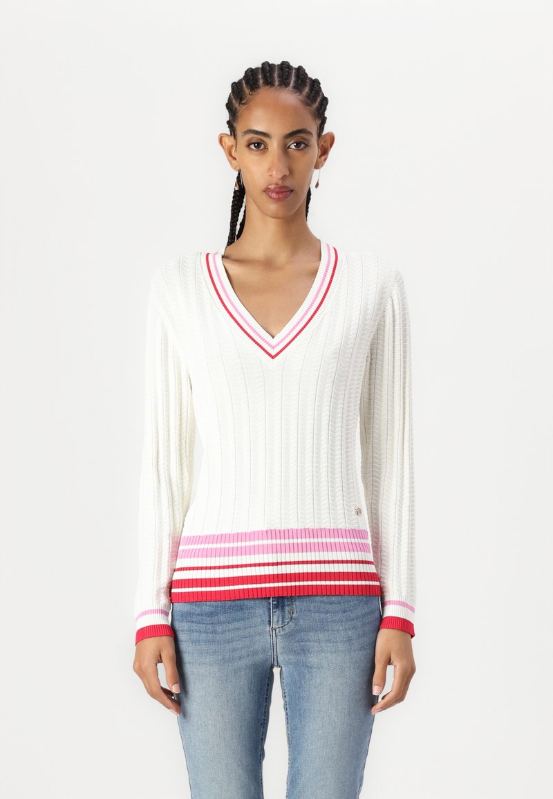 Maglione bianco a coste con scollatura a V, con dettagli a strisce rosse, rosa e bianche lungo l'orlo e i polsini delle maniche. Tessuto a maglia morbido.