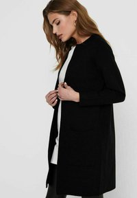 Black, long-sleeved coat made of textured fabric with a straight cut, featuring a round neckline and a front pocket.