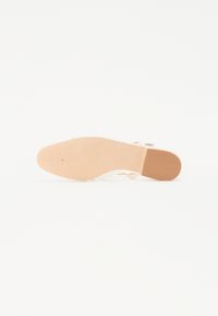 Sandalía de tacón alto transparente con suela de goma beige, tiras delgadas y plantilla texturizada, diseñada para la comodidad de los dedos al aire.