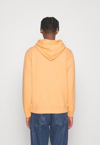 Sweat à capuche jaune en tissu doux, avec une poche kangourou, des poignets côtelés et une coupe décontractée. Vue de dos montrée.