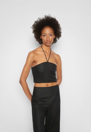 Top halter cropped preto com textura suave e design ajustado. Apresenta alças finas e decote reto. Emparelhado com calças pretas de cintura alta.