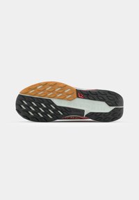 Black and gray rubber running shoe sole with orange accents. Features a textured tread pattern for grip and durability. Nike branding visible.