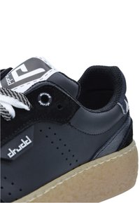 Czarne sneakersy z textured skórzaną cholewką, białymi sznurówkami i szarym gumowym podbiciem. Posiada perforacje i detal logo na bocznej części.