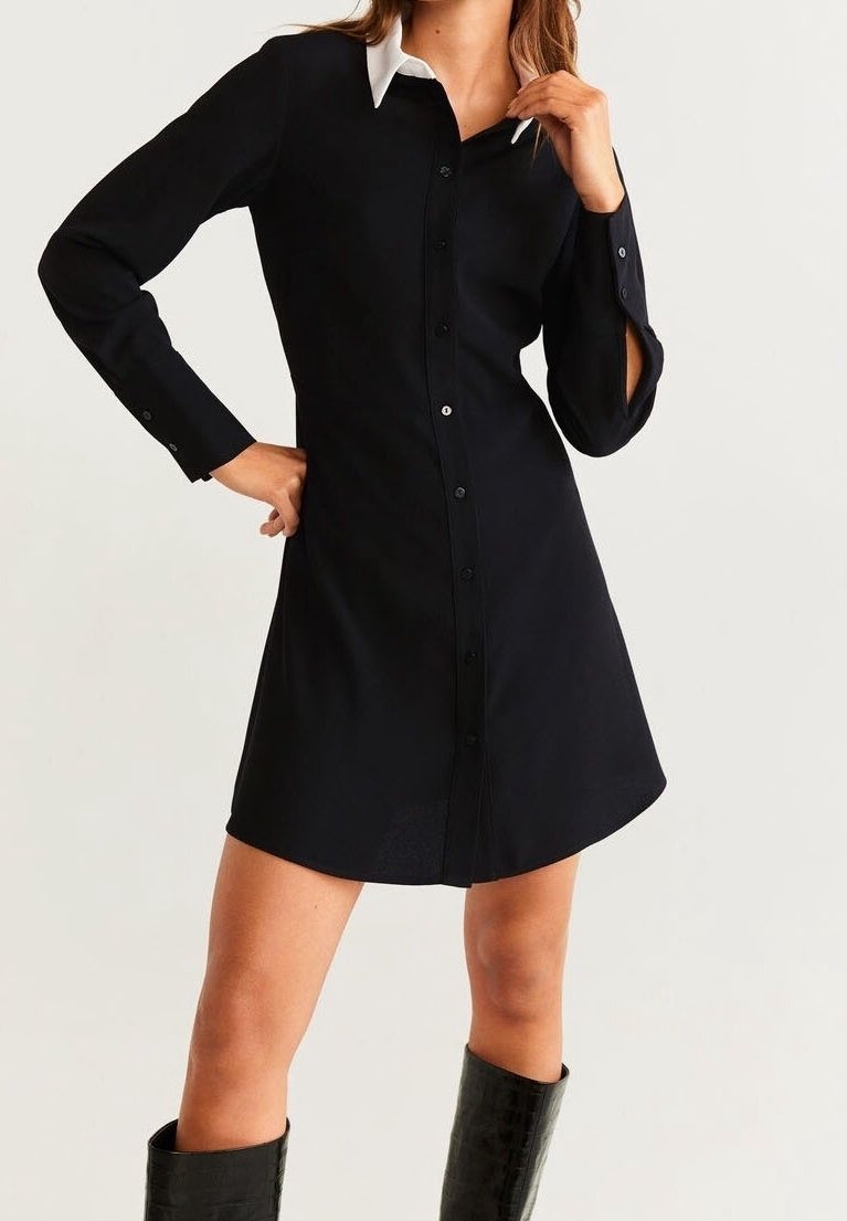 Robe noire boutonnée avec col blanc, manches longues avec découpes, et ourlet légèrement évasé, en tissu lisse.