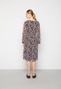 Vestido fluido de comprimento médio em tecido preto transparente, com um padrão floral em azul e rosa. Mangas longas com detalhe de cintura elástica.