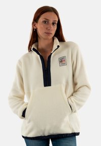 Pullover in pile bianco con zip e orlo navy, dotato di una tasca frontale e di un patch decorativo con design di palma e sole.