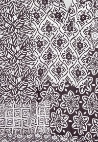 Schwarz-weiß gemusteter Stoff mit floralen und geometrischen Designs. Deutliche Abschnitte mit unterschiedlichen Motiven und Texturen durchgehend.