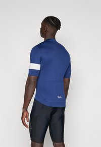 Kurzarm-Radsporttrikot in Marineblau mit weißen Schulterstreifen; verfügt über Rückentaschen, glatte Textur und Rapha-Logo am Saum.