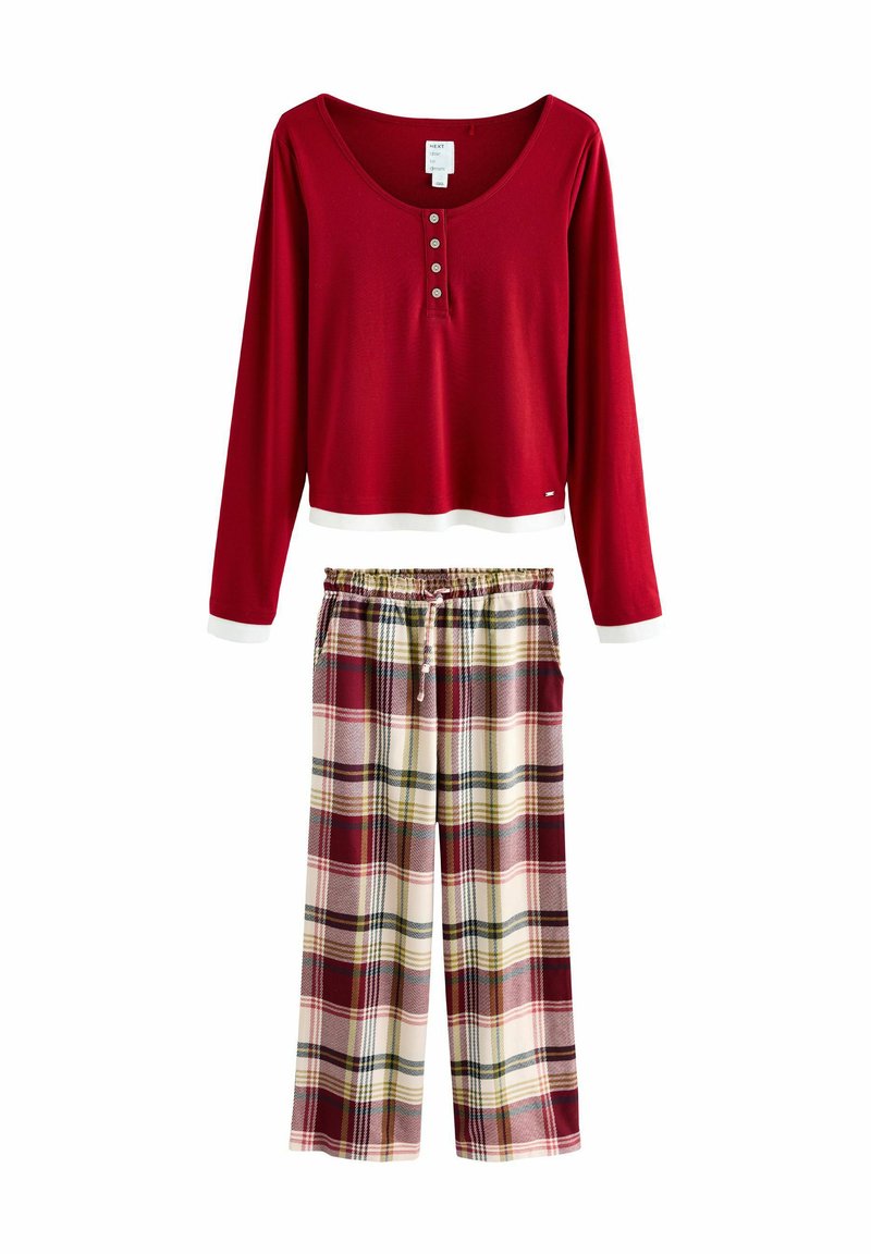 Punainen pitkähihaista paita nappidetaileilla ja valkoisilla hihoilla, yhdistettynä ruutuhousuihin punaisen, valkoisen ja vihreän sävyissä, joissa on joustava vyötärö.