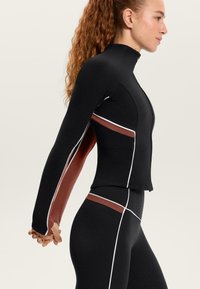 Schwarze Sportjacke mit langen Ärmeln, ausgestattet mit burgunderfarbenen Seitenteilen und weißen Akzentlinien, entworfen für eine körperbetonte Silhouette.