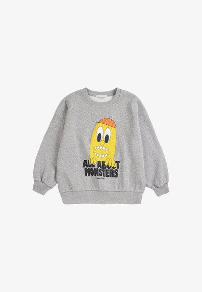 Felpa grigia a maniche lunghe con un mostro giallo dei cartoni animati che indossa un cappello arancione e il testo "All About Monsters" sulla parte anteriore.