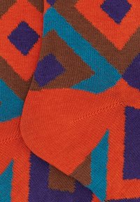 Calzini multicolori con un motivo geometrico a diamante in arancione, blu, marrone e viola. Realizzati in tessuto morbido e strutturato.