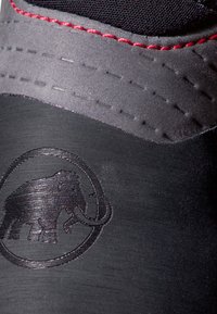 Czarny but wspinaczkowy z teksturowaną, matową powierzchnią, czerwonymi szwami i wypukłym logo słonia z boku.