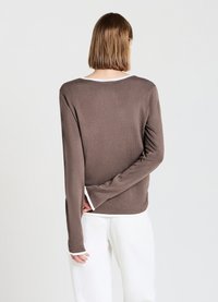 Camicetta marrone a maniche lunghe con bordo bianco al collo e ai polsini. Tessuto morbido e vestibilità comoda, con dettaglio di spacco sul retro.