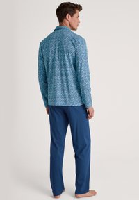 Blauw gestippeld overhemd met lange mouwen en een geometrisch patroon, gecombineerd met effen blauwe broek. Zachte stof, relaxed fit en open kraagstijl.