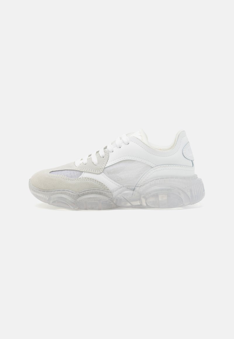 Sneakers with a white and light gray mix of leather and suede, featuring a transparent rubber sole, lacing, and subtle side detailing.
