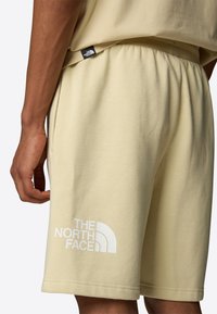 Svetle žluté bavlněné šortky s elastickým pasem, na levém stehně s velkým bílým logem "The North Face".