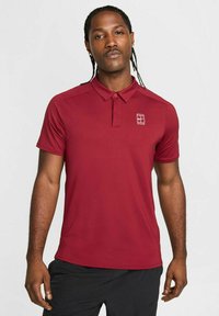 Bordeaux poloshirt med krave, korte ærmer og et lille logo på venstre bryst. Har en glat tekstur og klassisk pasform.