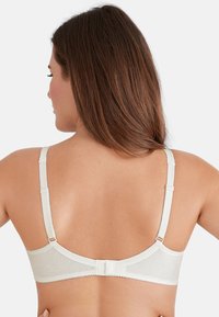 Lichtcrème beha met een gestructureerd golvend patroon, verstelbare bandjes en een haak-en-oogsluiting aan de achterkant. Gladde stof, eenvoudig ontwerp.