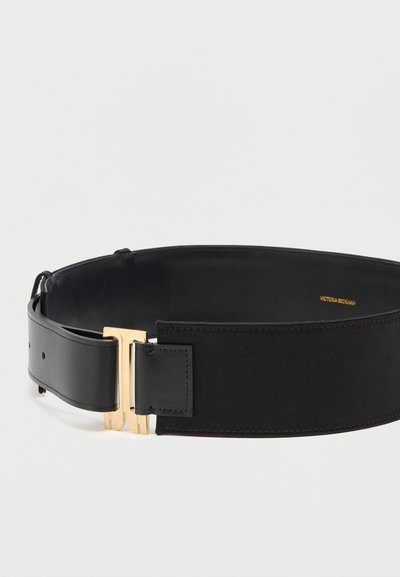 Μαύρη φαρδιά ζώνη με ελαστικό ύφασμα στο πίσω μέρος, λείο δέρμα στο μπροστινό μέρος και διπλή αγκράφα "VB" σε χρυσό τόνο, με ετικέτα Victoria Beckham στο εσωτερικό.