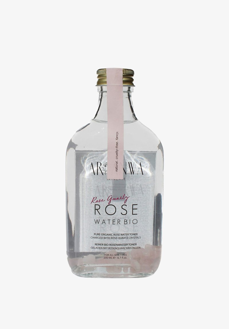 Bouteille en verre transparente contenant 200 ml de tonique à l'eau de rose, avec une étiquette rose, un bouchon doré et des cristaux de quartz rose visibles à la base.