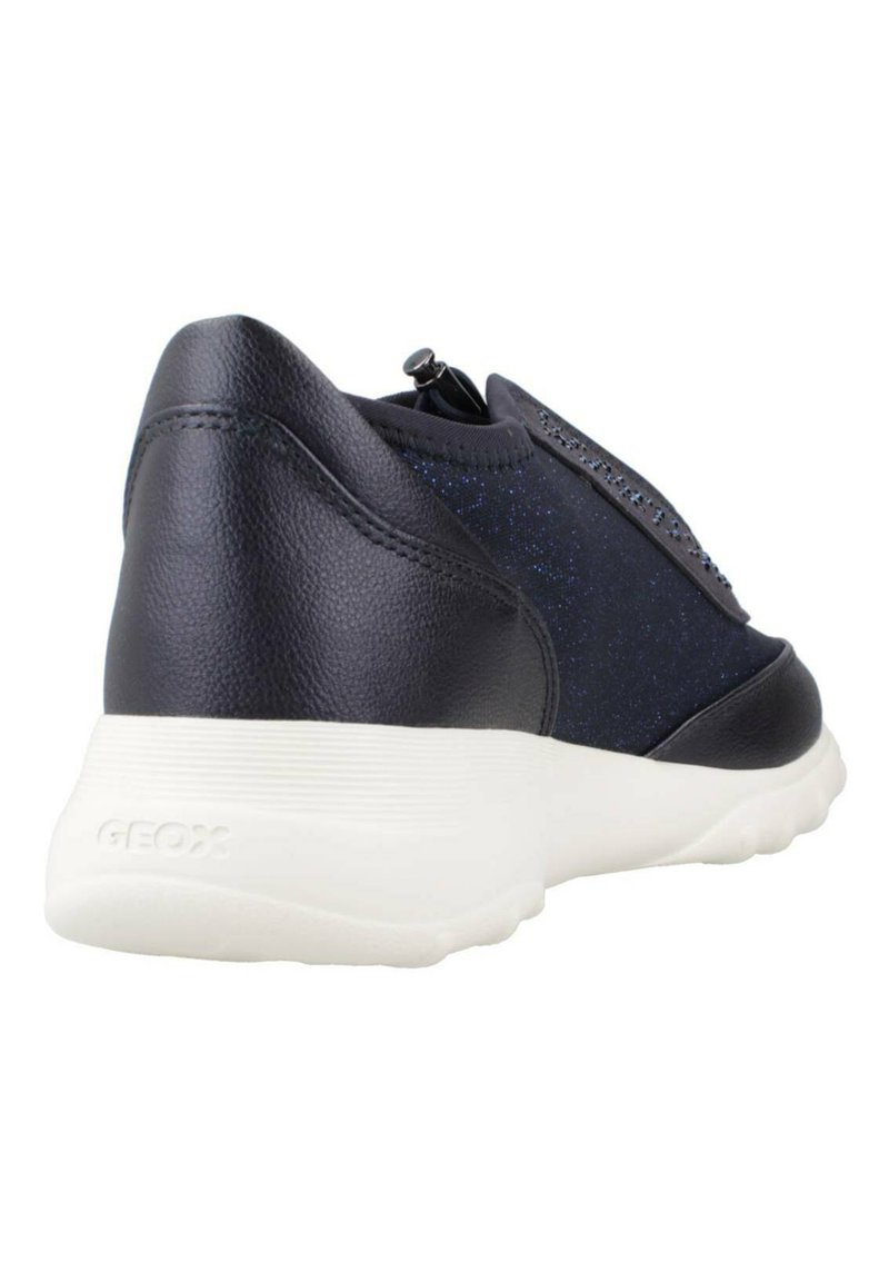 Zapatilla de cuero negra con parte superior texturada y brillante, y suela blanca acolchada. Cuenta con cierre de cremallera y logo en relieve en el lateral.