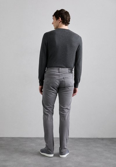 Suéter gris y chinos gris de corte slim. Las zapatillas son de un gris claro con suelas blancas. La textura parece suave, con un diseño minimalista.