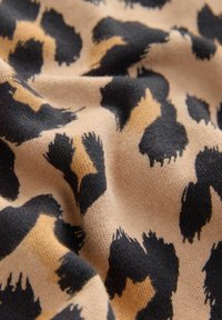 Tissu à motif léopard avec une texture douce, présentant de grandes taches noires sur un fond beige, créant un motif dynamique.