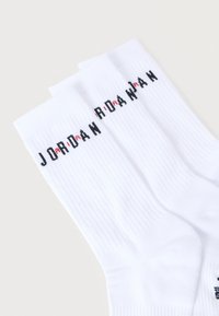 Λευκές κάλτσες για ομάδα με ριμπ υφή και μαύρο κείμενο "JORDAN" με κόκκινες λεπτομέρειες. Τρία ζευγάρια τοποθετημένα το ένα πάνω στο άλλο.