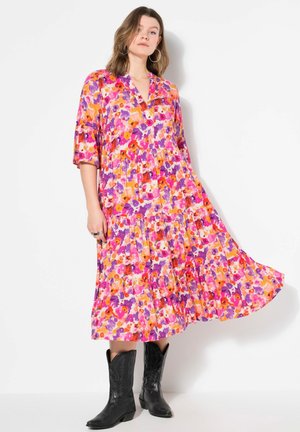 Blumiges Maxikleid mit einem V-Ausschnitt, 3/4-Ärmeln und einem gestuften Design. Die Farben umfassen Pink, Lila und Orange auf einem hellen Hintergrund.
