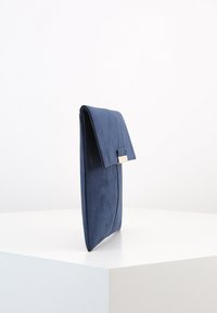 Námorně modrá psaníčko s měkkou texturou, elegantním designem a kovovým zapínáním. Obsahuje překlopený klopový uzávěr a hladký, zakřivený šev.