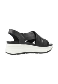 Sandali in pelle nera con fasce incrociate, una robusta suola intermedia bianca e una suola esterna nera testurizzata. Design aperto sul retro per una facilità di utilizzo.