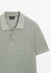 Polo shirt grigio chiaro realizzato in tessuto jersey, con colletto classico, tre bottoni e maniche corte. Texture delicata su tutta la superficie.