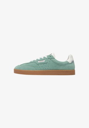 Sneaker in pelle scamosciata verde a profilo basso con lacci bianchi, suola marrone, linguetta posteriore bianca e logo "Faguo" sul lato.