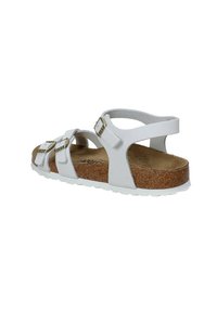 Sandali bianchi con tre cinture regolabili, fibbie dorate, soletta in sughero e suola in gomma bianca. Design aperto sul retro per facilitare l'indossaggio.