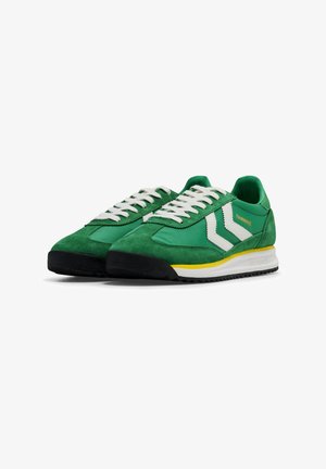 Paar grüne Wildleder- und Stoff-Sneaker mit weißen Schnürsenkeln, weißen Chevron-Streifen, gelbem Akzent auf der Zwischensohle und schwarzer Gummisohle.