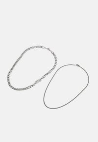 Duas correntes de prata: uma com um fecho robusto e a outra uma corrente fina e delicada. Ambas possuem um acabamento metálico suave e um brilho subtil.