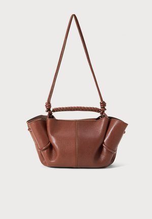 Sac à main en cuir marron avec une poignée tressée et une bandoulière réglable. Présente des côtés doucement pliés et des accents de couture visibles.