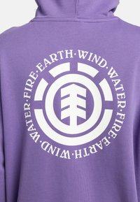 Purple hoodie featuring a circular white graphic with symbols for earth, wind, water, and fire, centered on the back.
