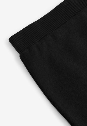 Pantaloni de trening negri cu un talie ribbată și o textură a materialului moale și neted. Concentrați-vă pe detaliile de la tiv.