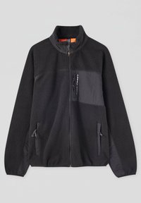 Černá fleecová bunda s vysokým límcem, kontrastní matnou látkovou panelem, zipovou kapsou na hrudi a bočními kapsami. Textura je měkká a nadýchaná.