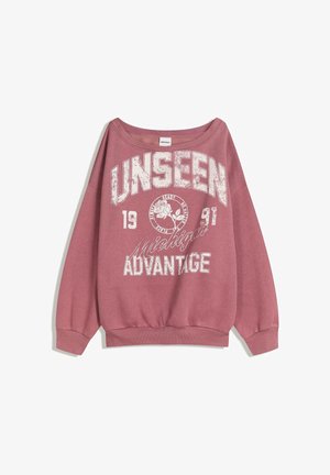 Ružičasta majica s širokim izrezom. Sadrži grafički natpis "UNSEEN" i "ADVANTAGE" u bijeloj boji, s vintage detaljima i opuštenim krojem.