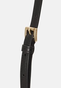 Černý kožený pásek s nastavitelnou přezkou, vybavený zlatým kováním a hladkou texturou, zdobený prošíváním a děrovanými dírkami.