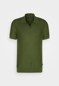 Polo manches courtes vert olive avec col et ouverture en V, tissu texturé et petite étiquette de marque sur la couture latérale.