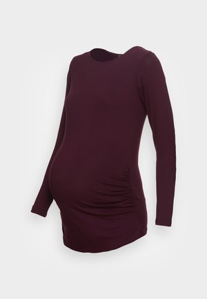 Langärmliges, tailliertes Umstandsshirt in dunklem Pflaumenton mit rundem Ausschnitt und seitlichen Raffungen im Bauchbereich.