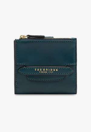 Cartera compacta de piel en verde azulado oscuro con cremallera dorada y «THE BRIDGE FIRENZE 1969» grabado en la correa frontal.