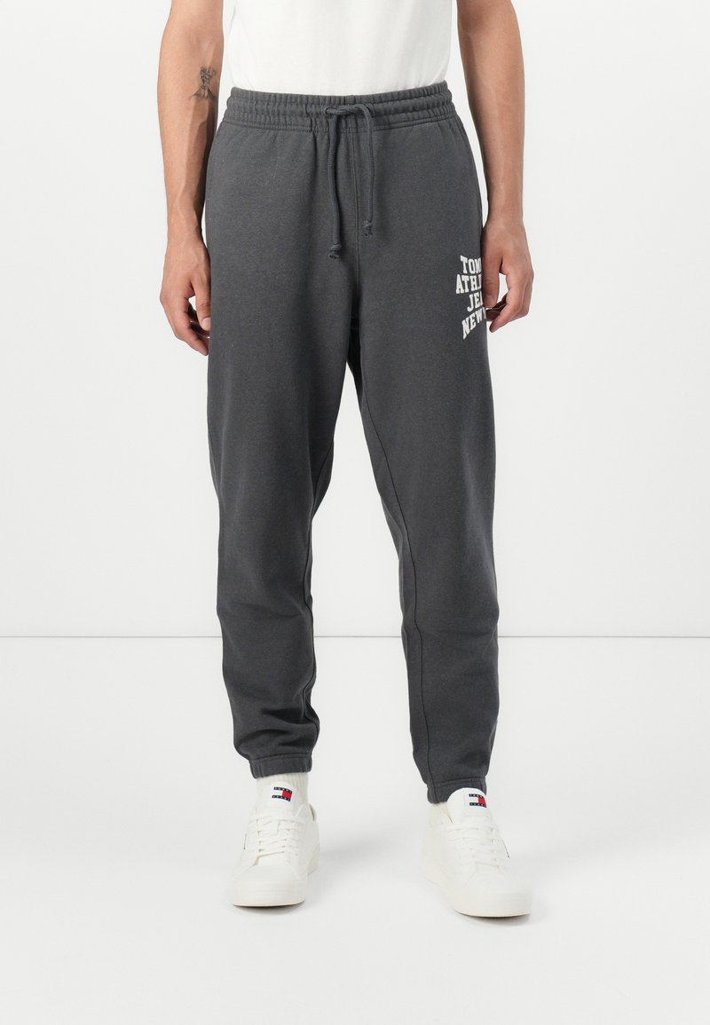 Grijze sweatpants met elastische tailleband en trekkoord, voorzien van witte gedrukte tekst aan de voorkant. Zacht stof en tapered ontwerp van de pijpen.