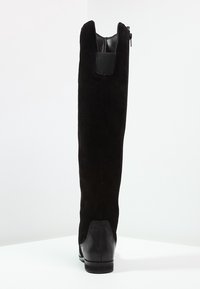 Stivali neri alti fino al ginocchio con tomaia in suede, chiusura con zip e tacco in pelle liscia. Il design presenta una silhouette elegante e aderente.